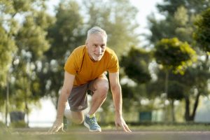 Senior man preparing for a run in a park, embracing fitness and active lifestyle